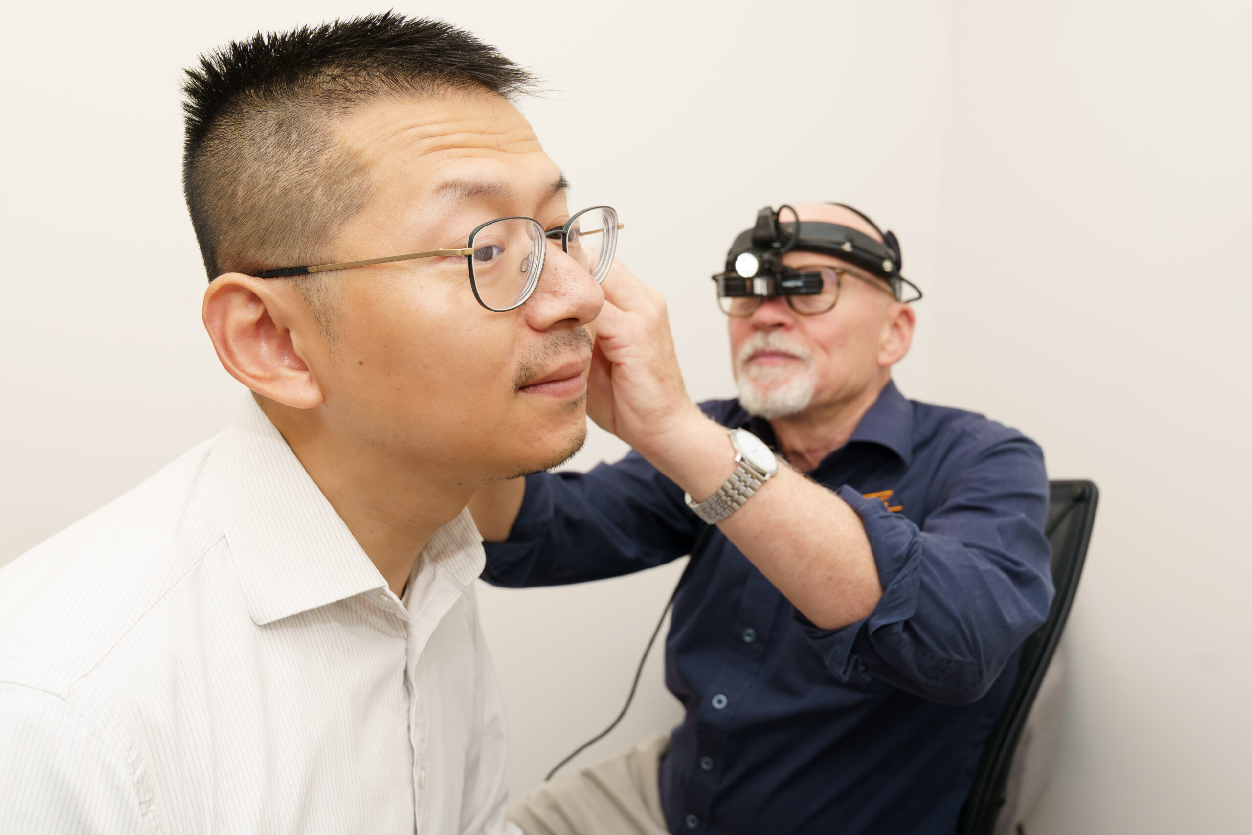 Audiologist examining a patient’s ear using magnification